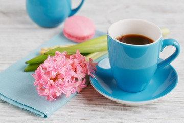 Fototapeta na wymiar Cup of black coffee, pink flowers and french macaroons