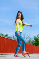 Teen girl skater riding skateboard on street.