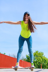 Teen girl skater riding skateboard on street.