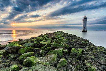 Photo sur Plexiglas Phare Lighthouse with moody dramatic clouds at sunset with algae rocks. New Brighton, Merseyside, UK.