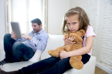  internet addict father using digital tablet pad ignoring little sad daughter bored hugging teddy bear