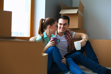 Portrait of young couple moving in new home sitting with cup