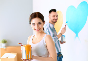 Portrait of happy smiling young couple  painting interior wall of new house