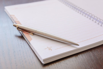 Naklejka premium Notebook with Blank sheet of paper and Pen on wooden table background