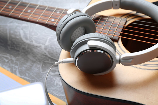 Classical guitar and headphones on grey background, close-up