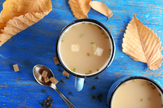 Two mugs of soup on blue wooden background