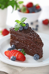 Chocolate cake with chocolate cream and fresh berries on plate, on light background