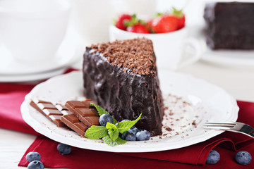 Chocolate cake with chocolate cream on plate, on light background