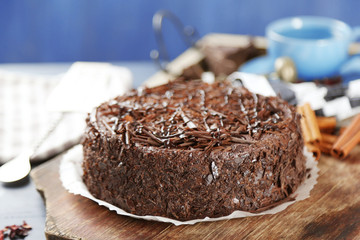 Tasty chocolate cake on color wooden background