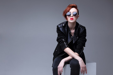 Redhead fashion model in sunglasses and black leather jacket