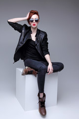 Redhead fashion model in sunglasses and black leather jacket