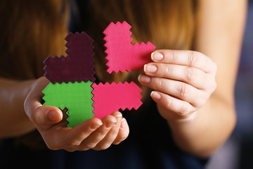 Closeup of plastic puzzle hearts in female hands