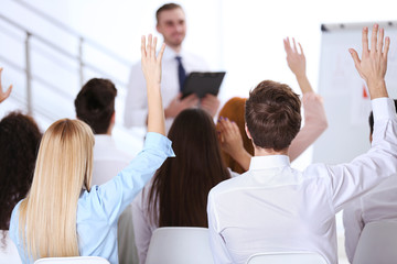 Young colleagues raising hands at the business meeting in office