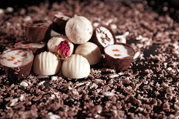 Assorted chocolate candies with flakes on black background