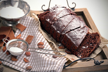 Chocolate sliced cake with icing and powdered sugar on a tray