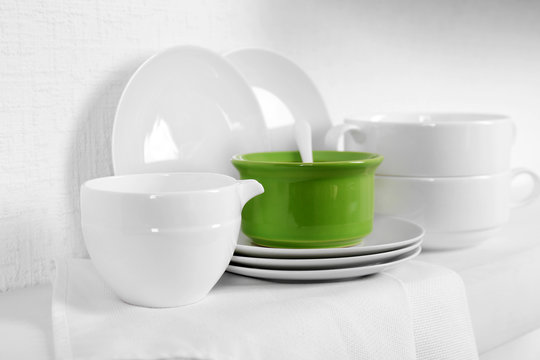 Set of tableware with napkin on shelf against white wall background
