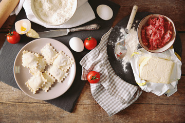 Uncooked ravioli on plate on wooden table
