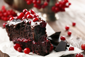 Piece of chocolate cake with cranberries on parchment, closeup