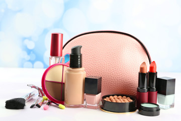 Makeup set with beautician, eyelash curler, brushes and cosmetics on light background