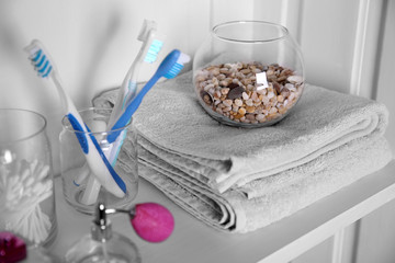 Bathroom set with towels, toothbrushes and perfume on a light shelf
