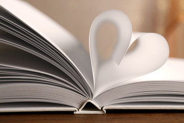 Heart from book pages on blurred background