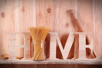 Home word with rolling pin and spaghetti on wooden background