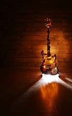 Electric guitar with lighted garland on dark wooden background