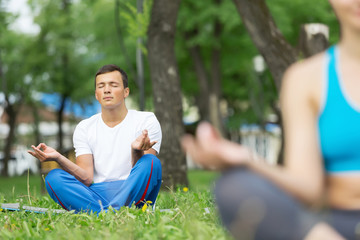 Obraz premium Young couple meditating on green grass