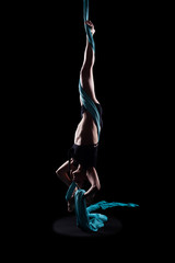 Young woman gymnast with blue gymnastic aerial silks