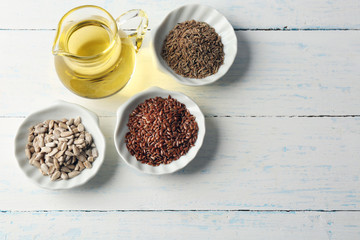 Different kinds of seeds and oil on wooden table