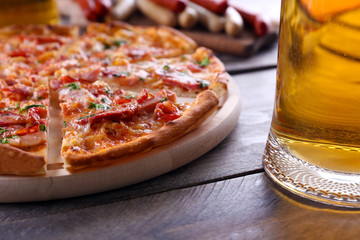 Sliced pizza and glass of beer on wooden table, close up