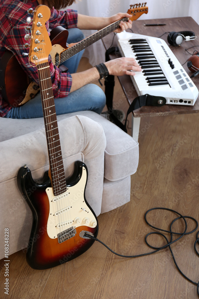 Wall mural Man with guitar and synthesizer indoors