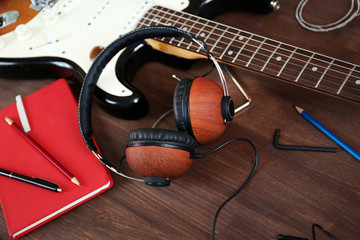 Naklejka premium Guitar with headphones on wooden surface closeup