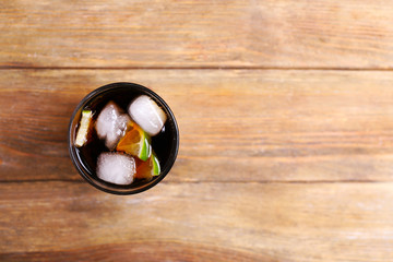 Cocktail with lime slices and ice blocks on wooden table, top view