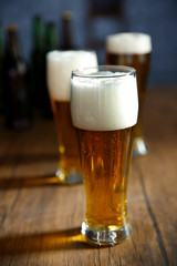 Three glasses of light beer on wooden table