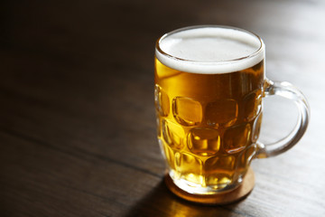 Glass mug of light beer on wooden table