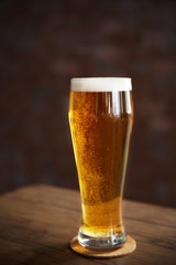 Glass of light beer on wooden table