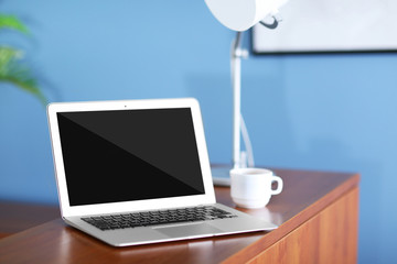Fototapeta premium Laptop and cup of coffee on wooden desk indoors