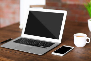 Fototapeta premium Workplace with laptop, mobile phone and cup of coffee indoors