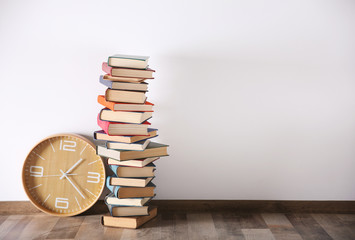 Pile of books and clock on floor at home