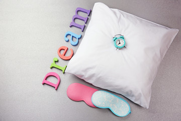Word Dream with pajamas, sleeping masks and little clock on a white pillow