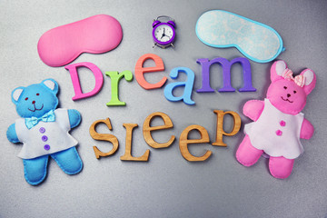 Words Dream and Sleep with  little toys  on a grey background