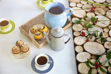 Cups of tea and cakes on wooden background