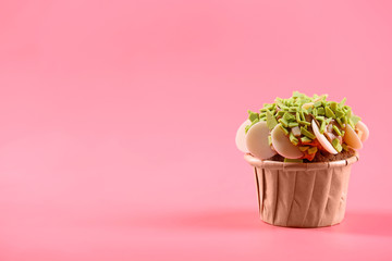 Tasty cupcake with original decoration on pink background