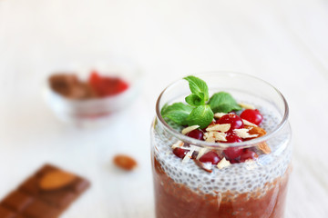 Chocolate chia seed pudding with cranberry and crushed almonds on wooden table