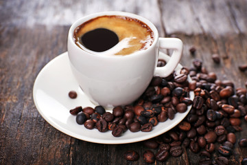 Cup of hot coffee with roasted beans on rustic wooden background