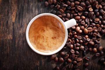 Cup of hot coffee with roasted beans on rustic wooden background