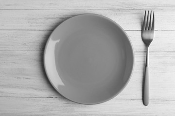Empty plate with silver fork on wooden background