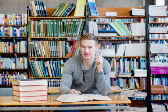 Male student in a library showing finger up