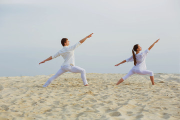  beautiful, athletic couple in white clothes making yoga exercis